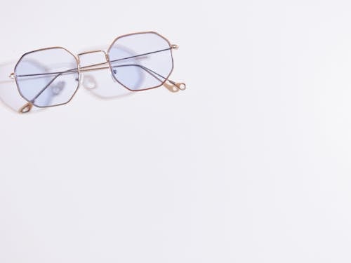 Gold Framed Eyeglasses on White Surface