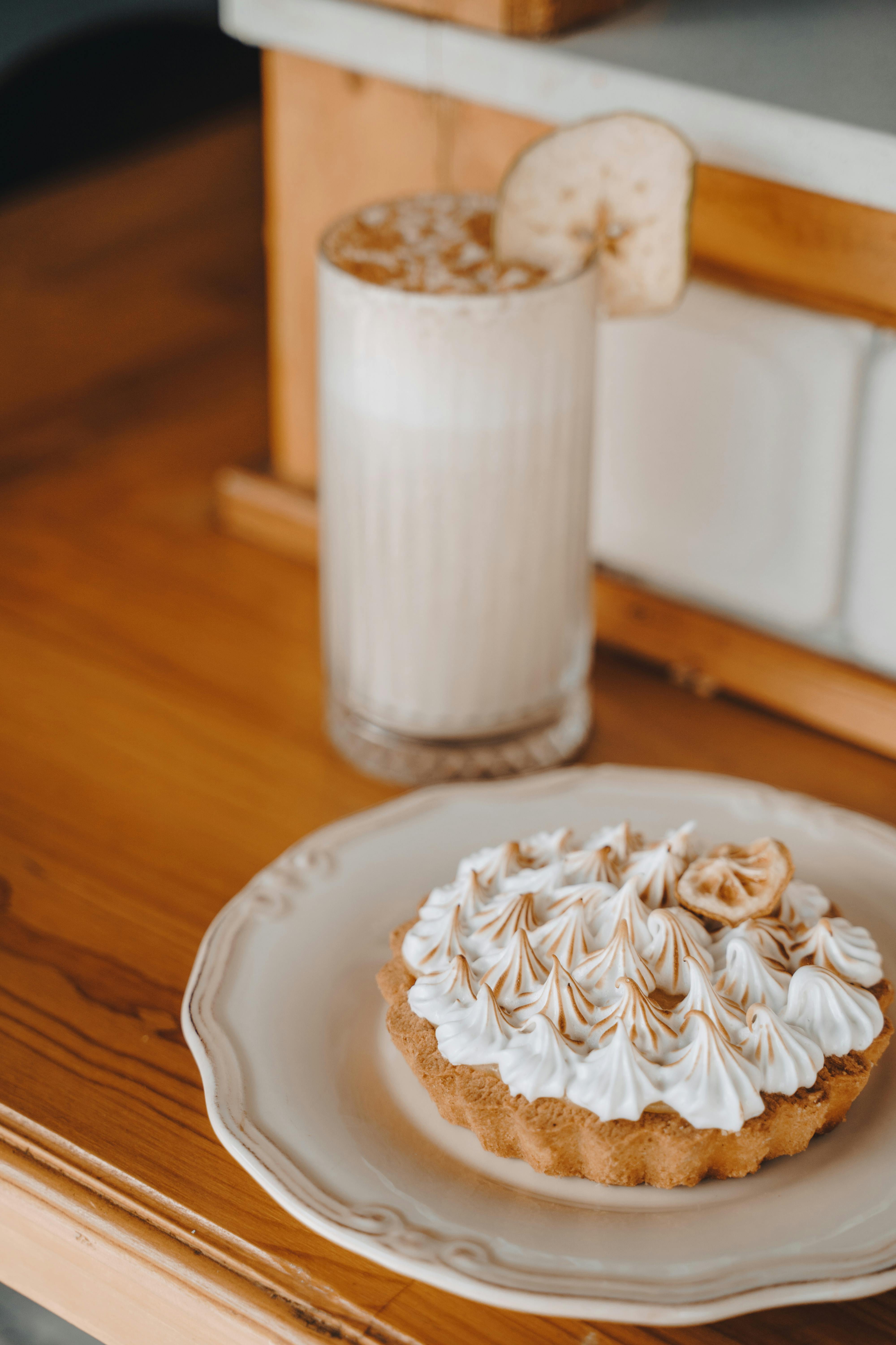 Delicious pie and creamy milkshake on a wooden table in a cozy café setting.