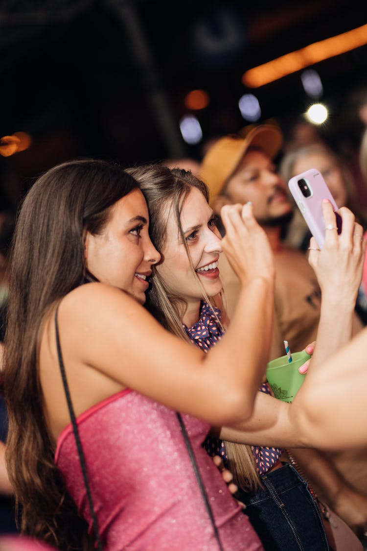 Photo Of Two Young Women Taking Pictures At A Concert