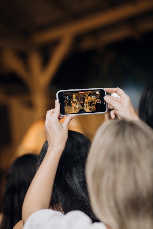 Photo of a Woman Taking Pictures During a Concert