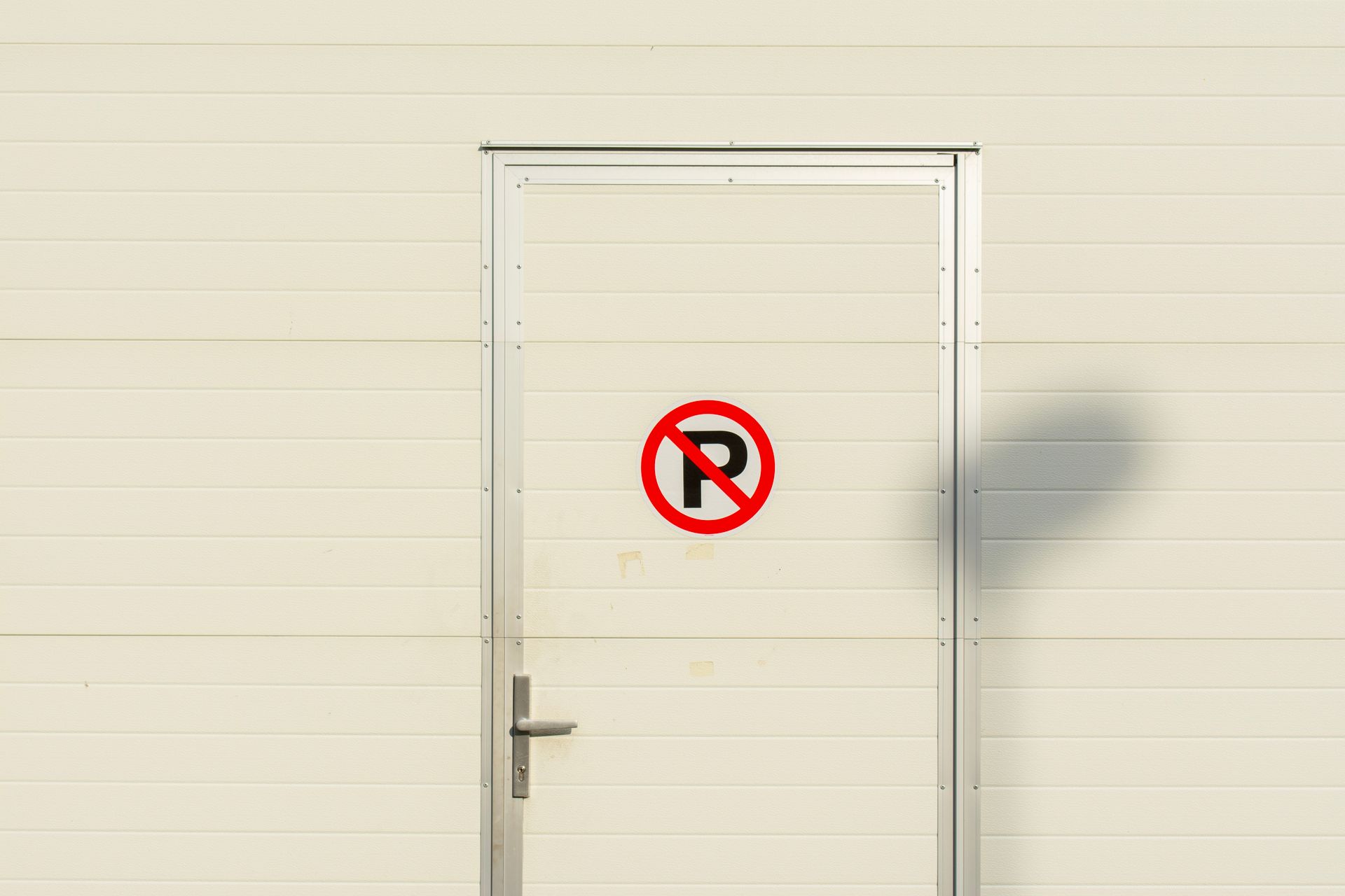 A white metal door with a no parking sign, perfect for industrial and urban themes.
