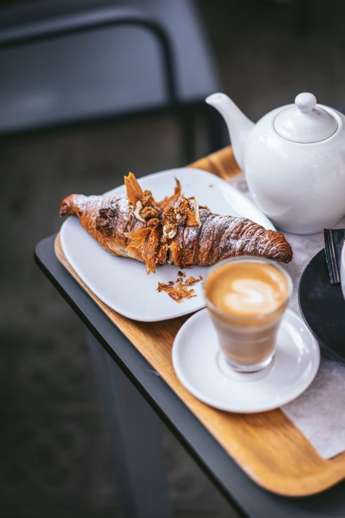 Free Aesthetic breakfast with a croissant, latte, and teapot on a tray. Stock Photo