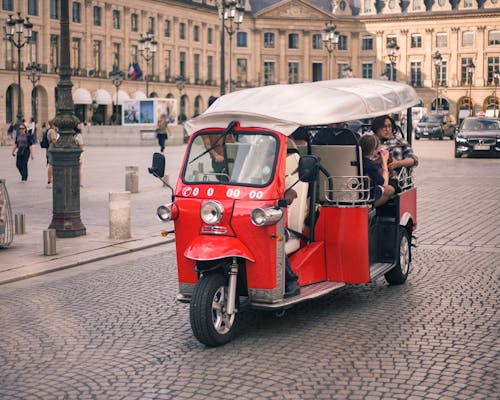 Tourists Riding a Red Piaggio Ape Calessino on Concrete Road