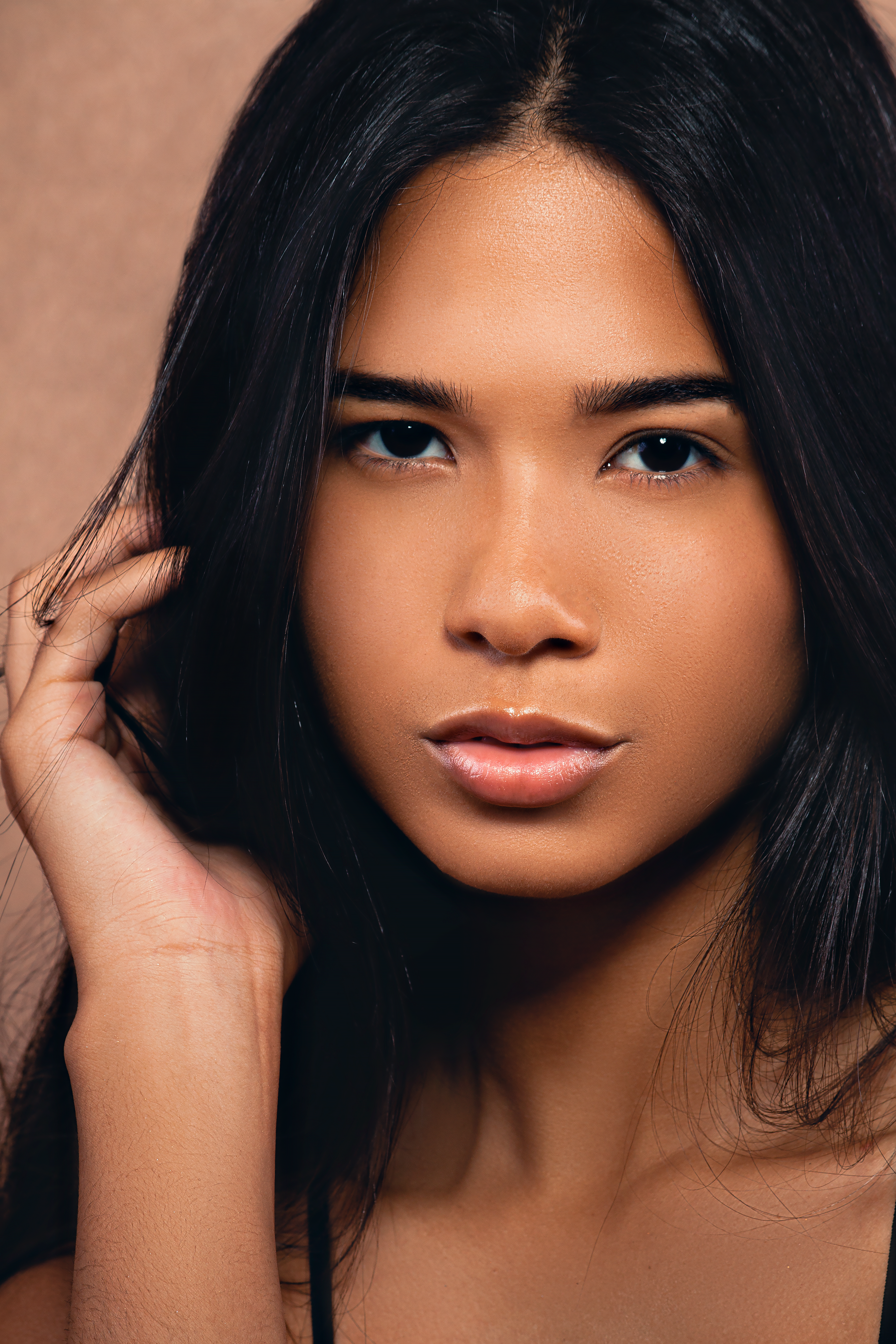 Captivating studio portrait of a woman with long black hair and a confident gaze.