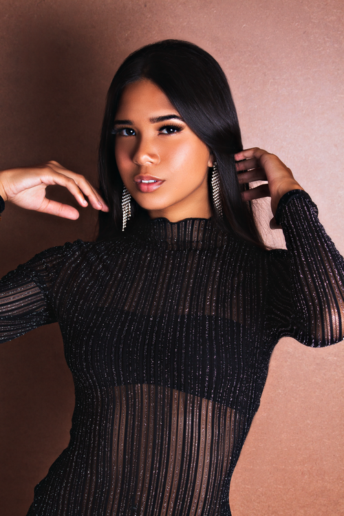 Free Stylish woman posing in a black sequined dress with long earrings in a studio setting. Stock Photo
