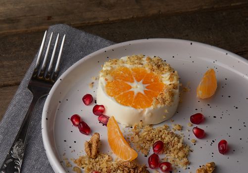 A gourmet dessert featuring orange slices, walnuts, and pomegranate seeds on a white plate.
