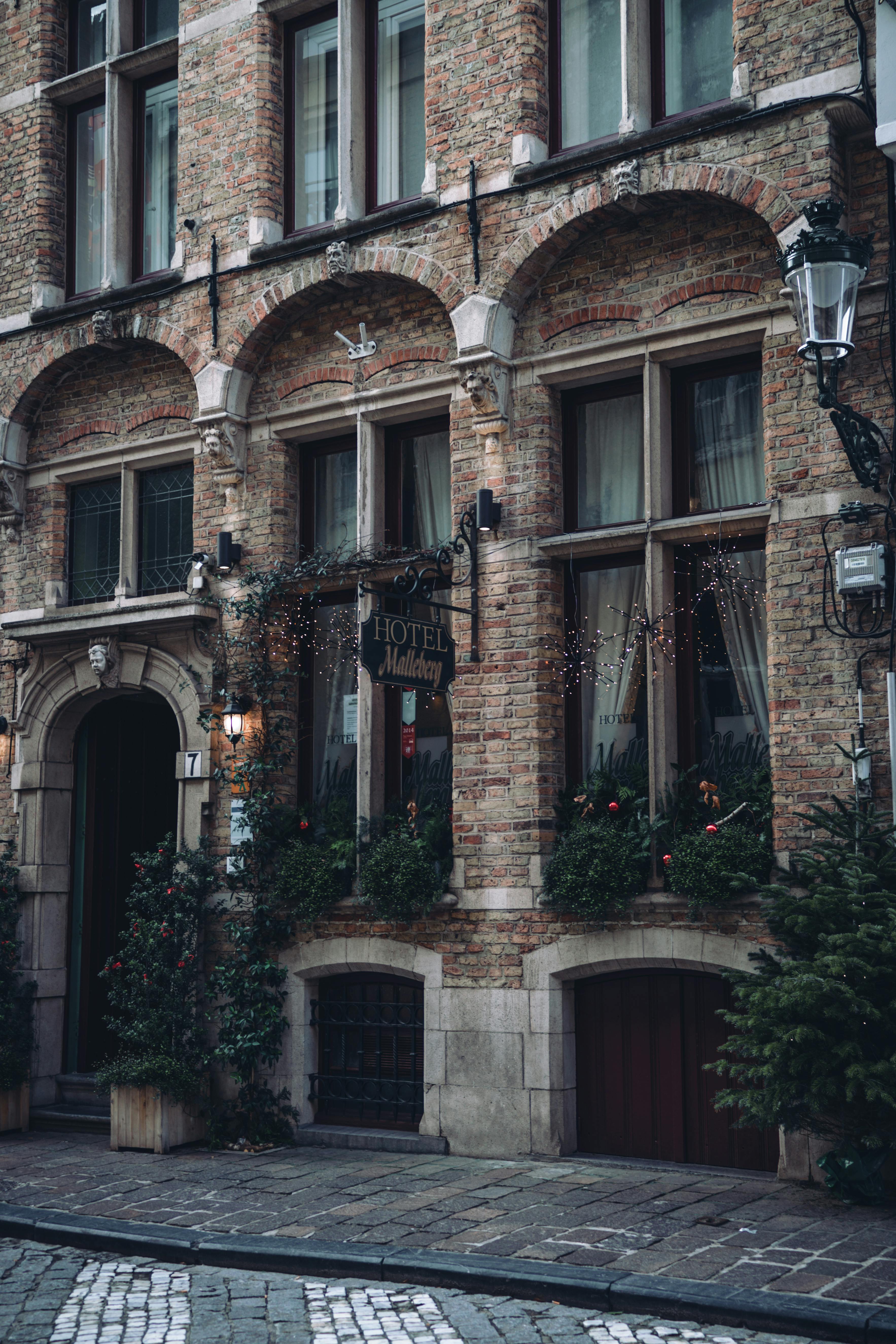 Beautiful brick hotel facade with arched windows and greenery on a quaint city street.