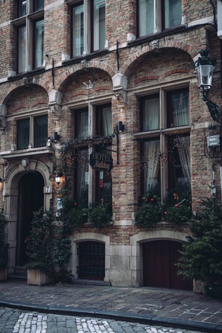 Beautiful brick hotel facade with arched windows and greenery on a quaint city street.