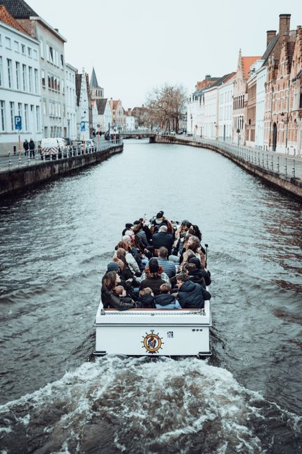 Tourists enjoy a scenic boat ride along a historic European canal with charming architecture.