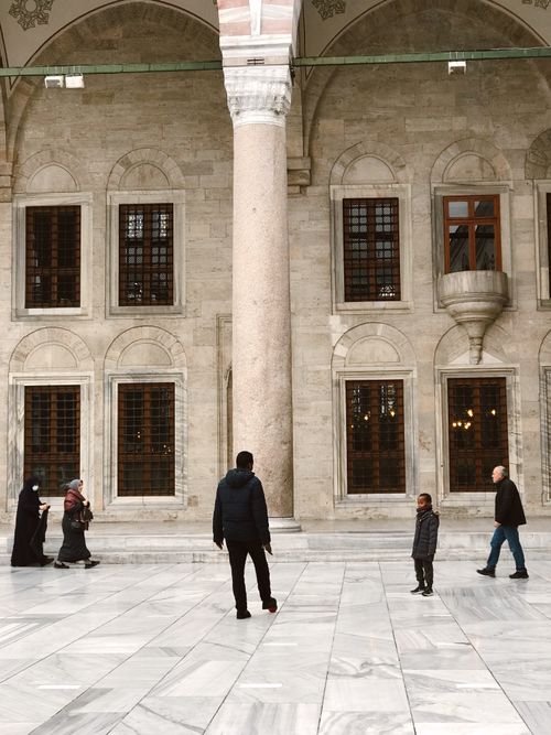 Free Visitors walking near a historic mosque's marble courtyard in Istanbul, Turkey. Stock Photo