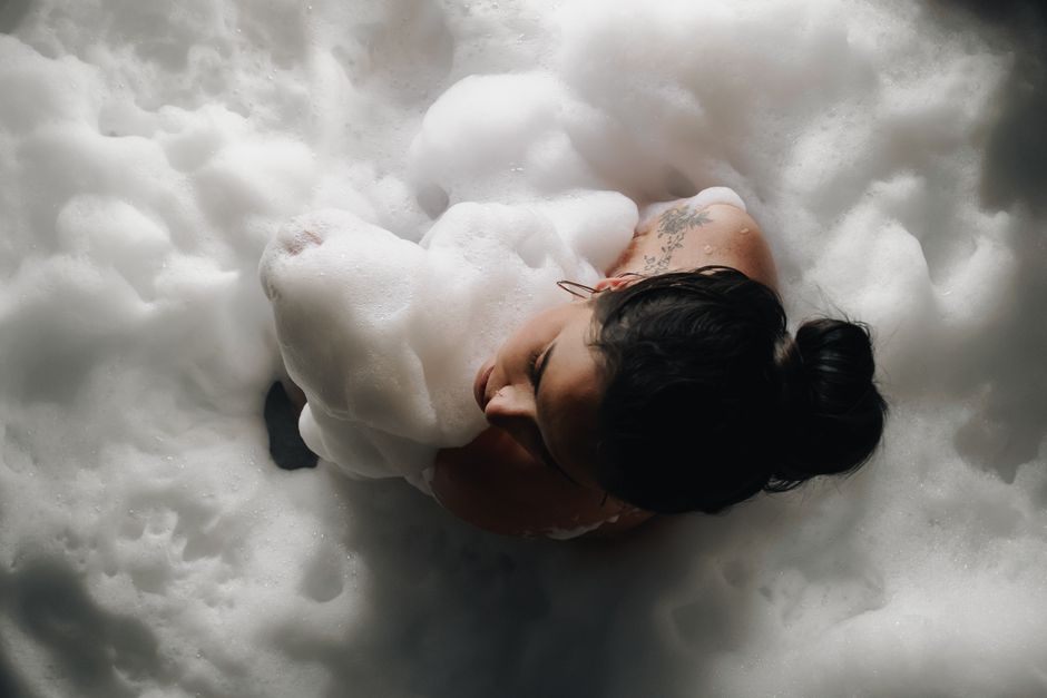 Top view of a woman relaxing in a foamy bathtub, embracing tranquility.