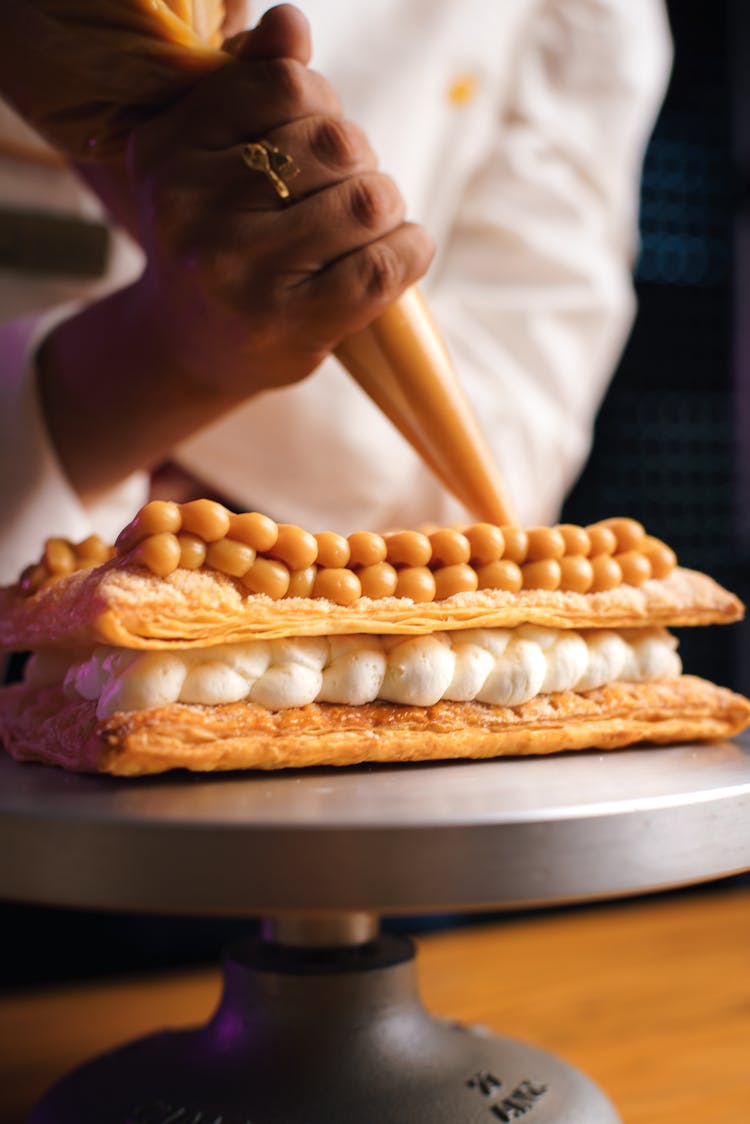 Baker Decorating A Dessert With A Pastry Bag