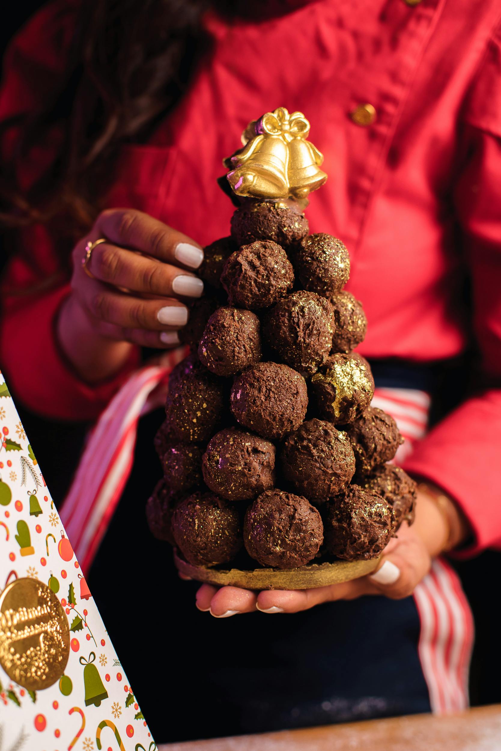 a woman holding a chocolate tree with a chocolate ball on top