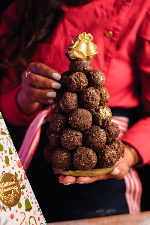 Woman Hands Holding Chocolate Balls in Christmas Tree Shape