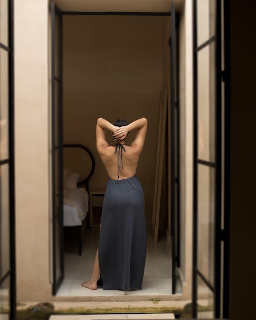 Woman in a Long Dress Standing in the Bedroom 