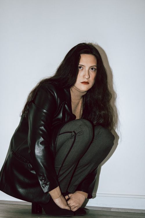 Free Elegant woman in leather jacket crouching for a stylish fashion portrait. Stock Photo