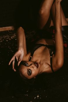 Stylish portrait of a woman posing elegantly in dark lingerie with dramatic lighting.