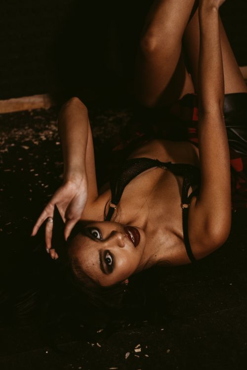 Free Stylish portrait of a woman posing elegantly in dark lingerie with dramatic lighting. Stock Photo