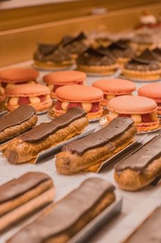 A close-up view of delectable pastries including eclairs and macarons in a bakery.