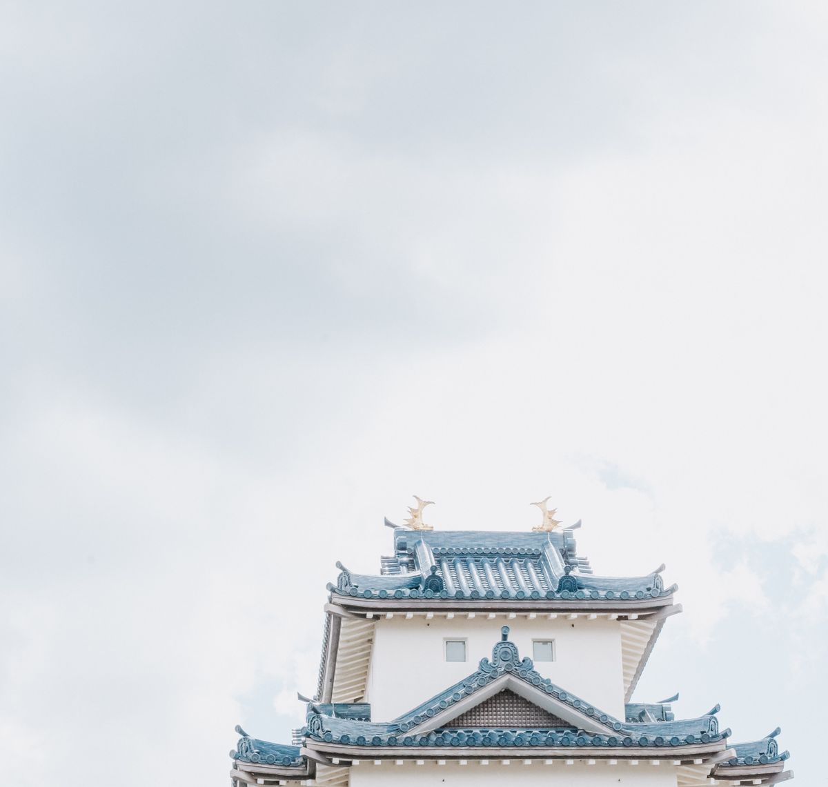 Elegant traditional Japanese castle rooftop against a bright sky