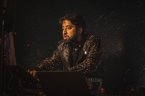 Man in a Leather Jacket Mixing Music on a Console 