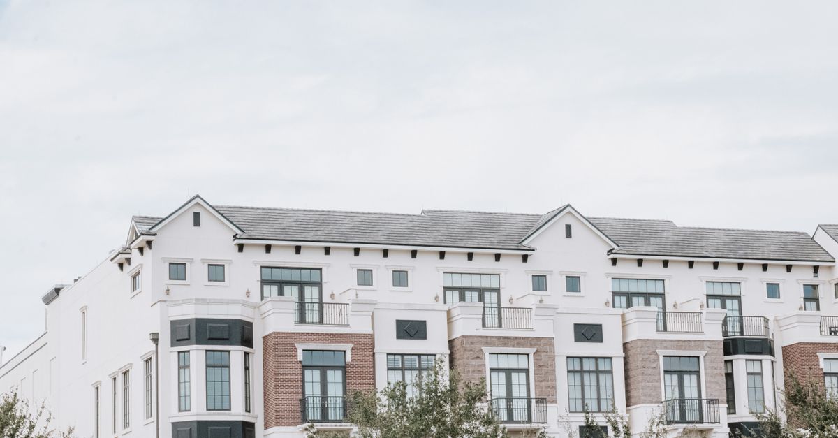 A stylish, multi-story luxury apartment building with a contemporary facade against a clear sky.