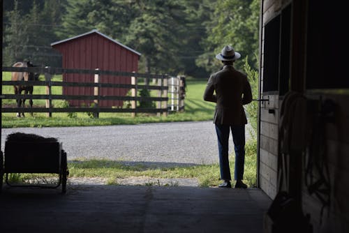 A Man Wearing a Blazer and a Hat in a Farm