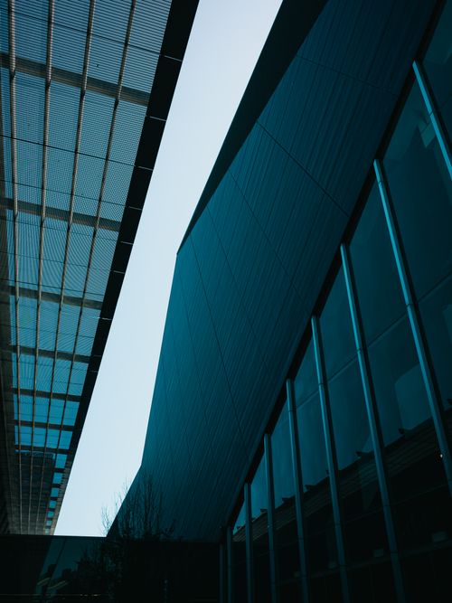 Free Low angle shot of a modern office building featuring sleek glass facade in urban setting. Stock Photo