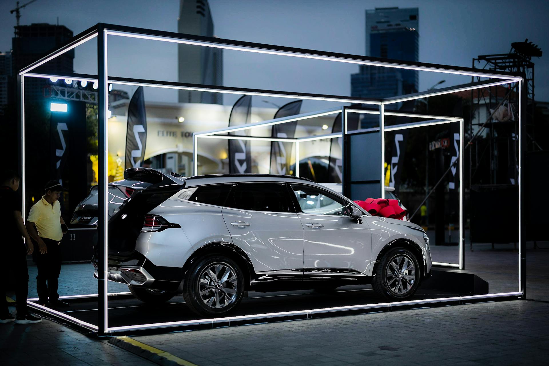 A sleek white SUV showcased in a vibrant nighttime auto show with illuminated frames.