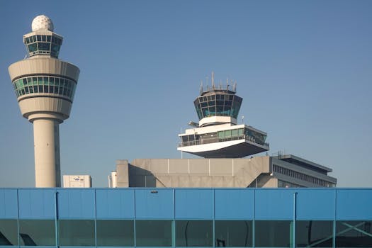 View of air traffic control towers at Amsterdam Schiphol Airport under clear blue sky.