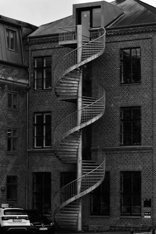 A Grayscale Photo of a Brick Building with Spiral Staircase