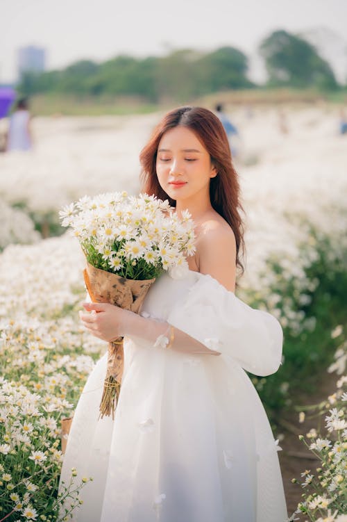 Free Beautiful Woman in White Dress Holding Bouquet of Flowers Stock Photo