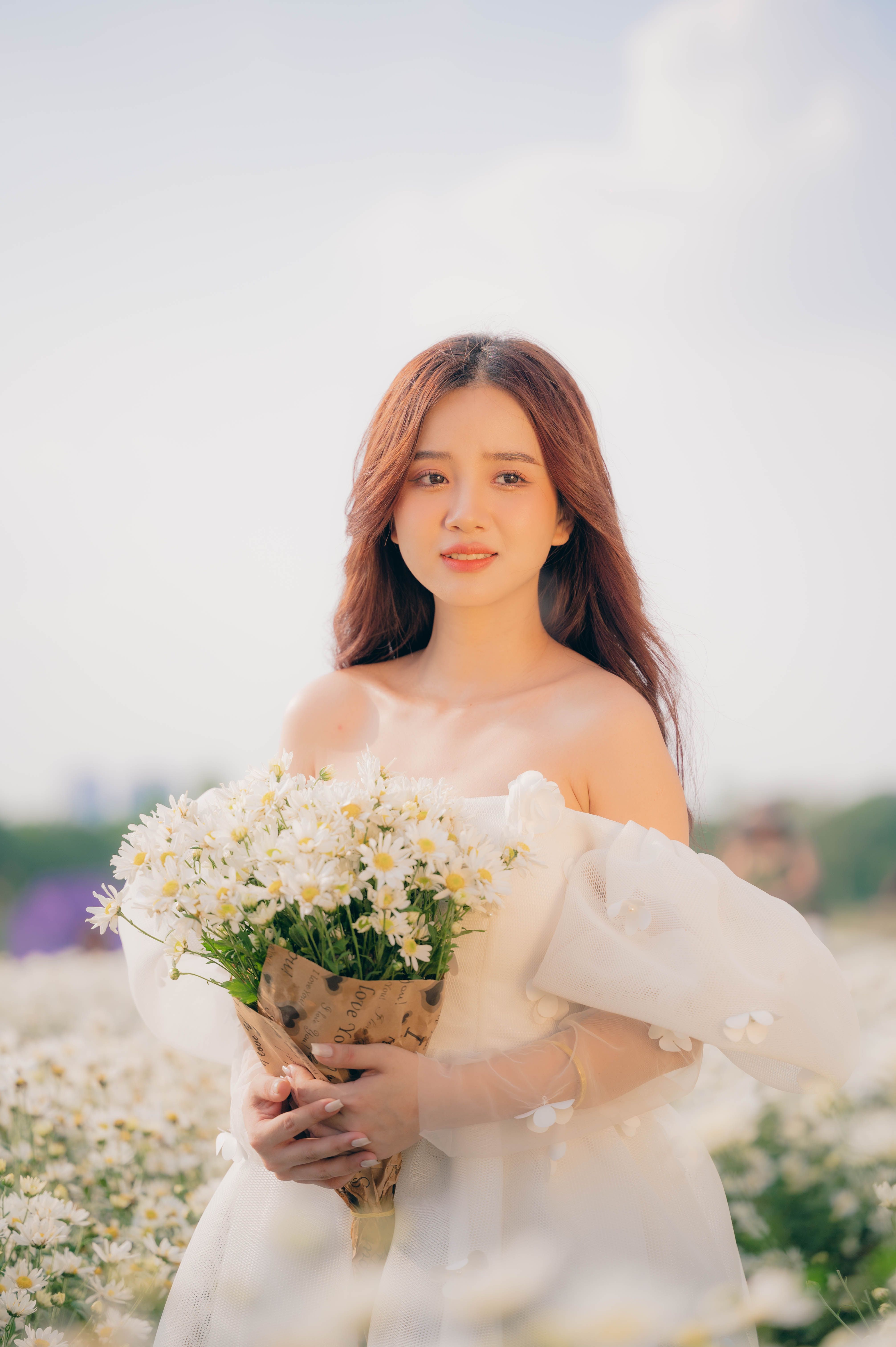 Woman in a White Dress Holding a Bouquet of Flowers · Free Stock Photo