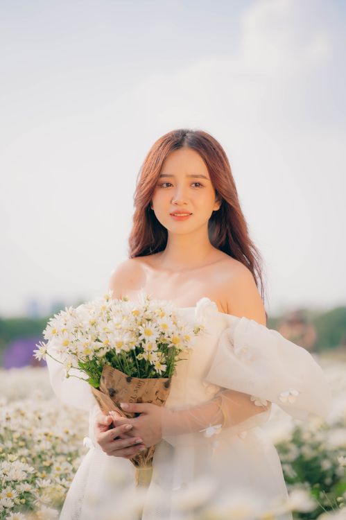 Woman in a White Dress Holding a Bouquet of Flowers · Free Stock Photo