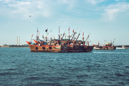 A vibrant view of fishing boats in Beyt Dwarka, India, with lively flags and calm waters.