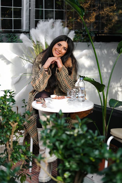 Young Brunette Woman Sitting at a Table in a Cafe 