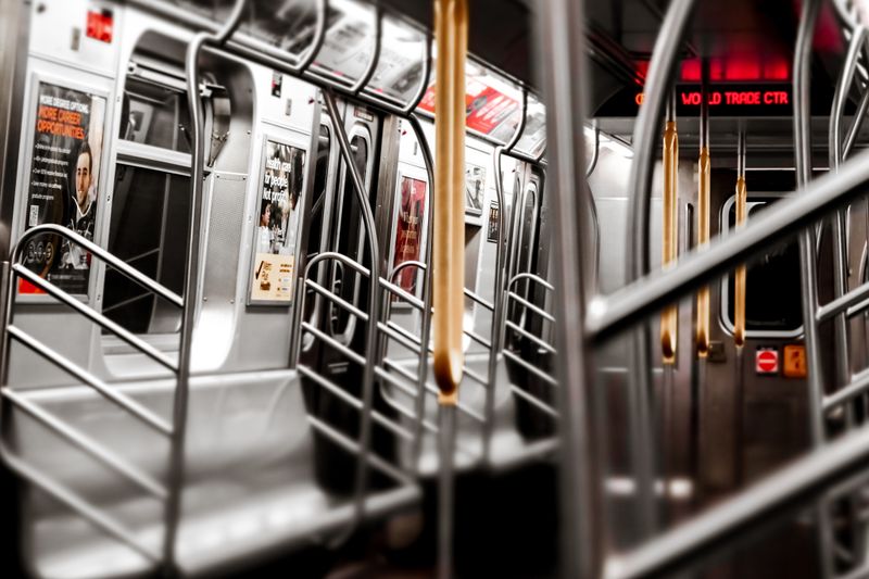 A view of an empty New York City subway car, showcasing the modern interior and advertisement posters.