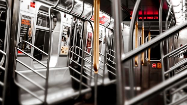 A view of an empty New York City subway car, showcasing the modern interior and advertisement posters.