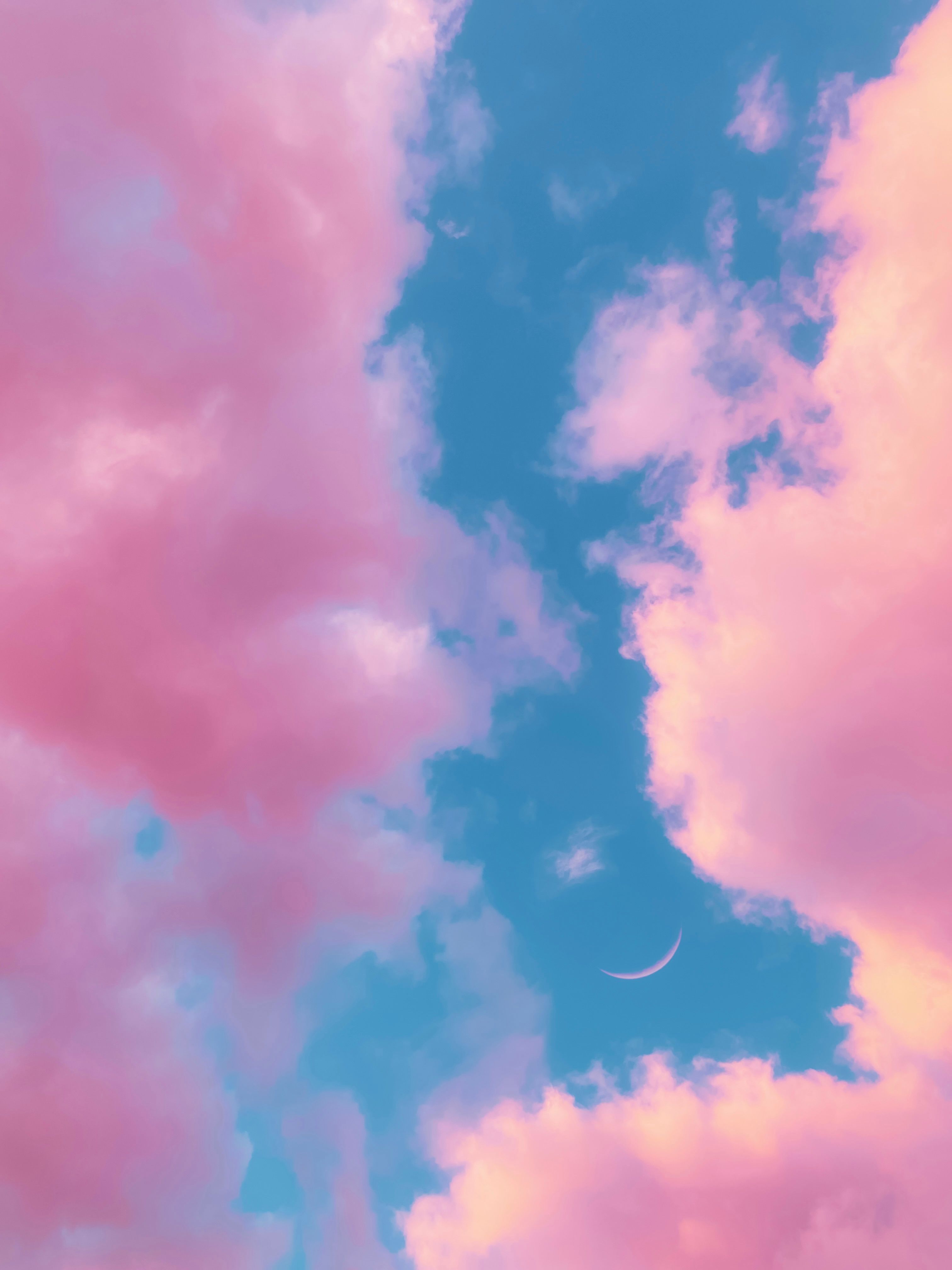 Dreamy pink clouds with a crescent moon in a vibrant sunset sky, capturing tranquility and beauty.