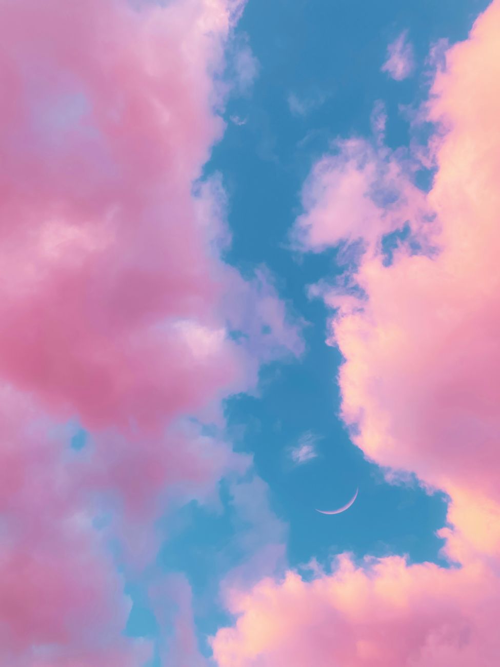 Dreamy pink clouds with a crescent moon in a vibrant sunset sky, capturing tranquility and beauty.
