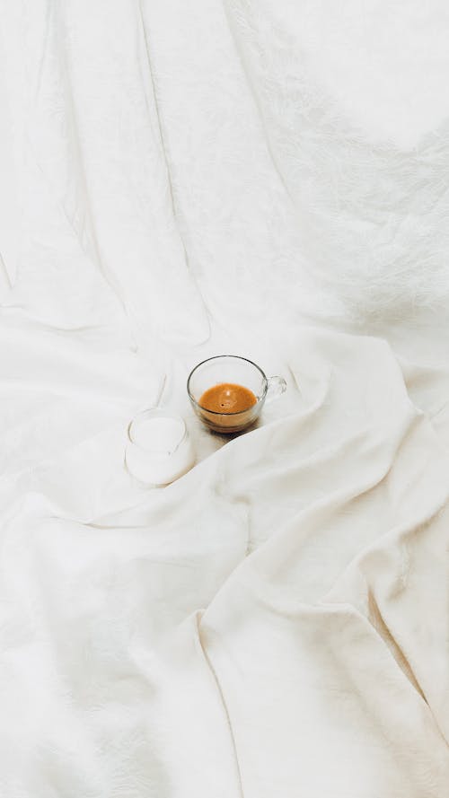 An Espresso and a Glass of Milk in White Bedsheets 