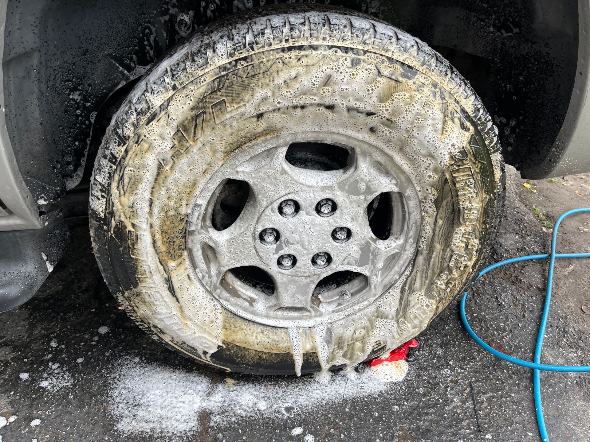 Close-up of a Car Wheel Covered in Foam in a Car Wash