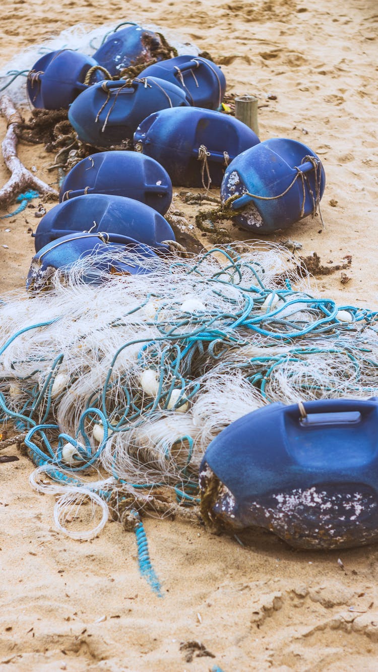 Blue Floaters And Tangled Net On Sand