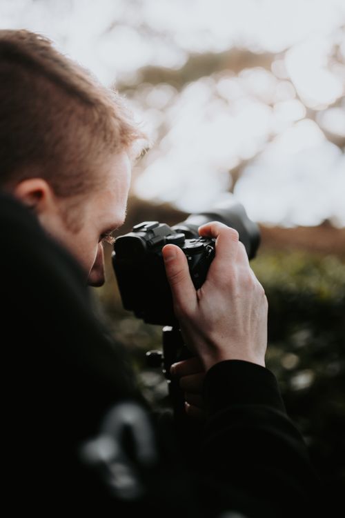 Free A focused photographer capturing the outdoors with a camera Stock Photo