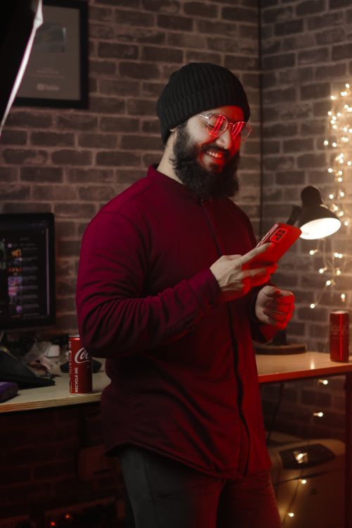 Free Bearded man in casual outfit enjoying smartphone in warm ambient lighting. Stock Photo