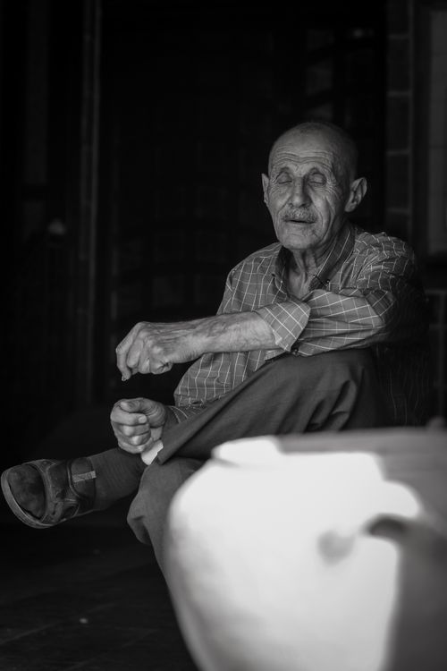 Free Black and white photo of an elderly man sitting indoors in Turkey, captured in moody lighting. Stock Photo