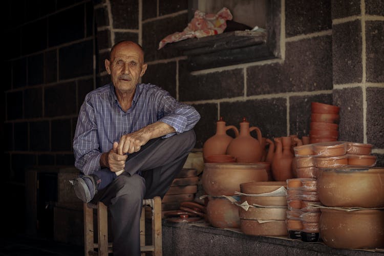 Man Sitting Next To Pottery