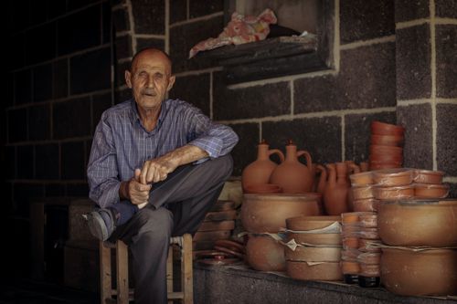 Free A senior man poses with handmade pottery in a traditional workshop in Diyarbakır, Turkey. Stock Photo