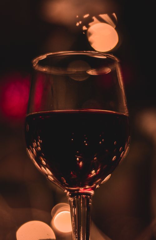 Free Glass of red wine with bokeh lights in warm, luxurious ambiance. Stock Photo