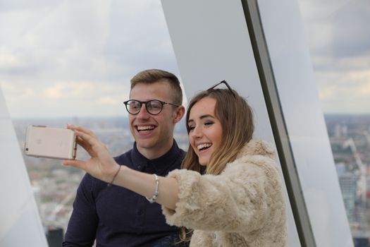Happy couple snapping a selfie with a London skyline view.